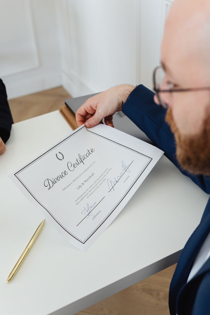 A man attentively reviewing a divorce certificate in an office setting, showcasing legal context.